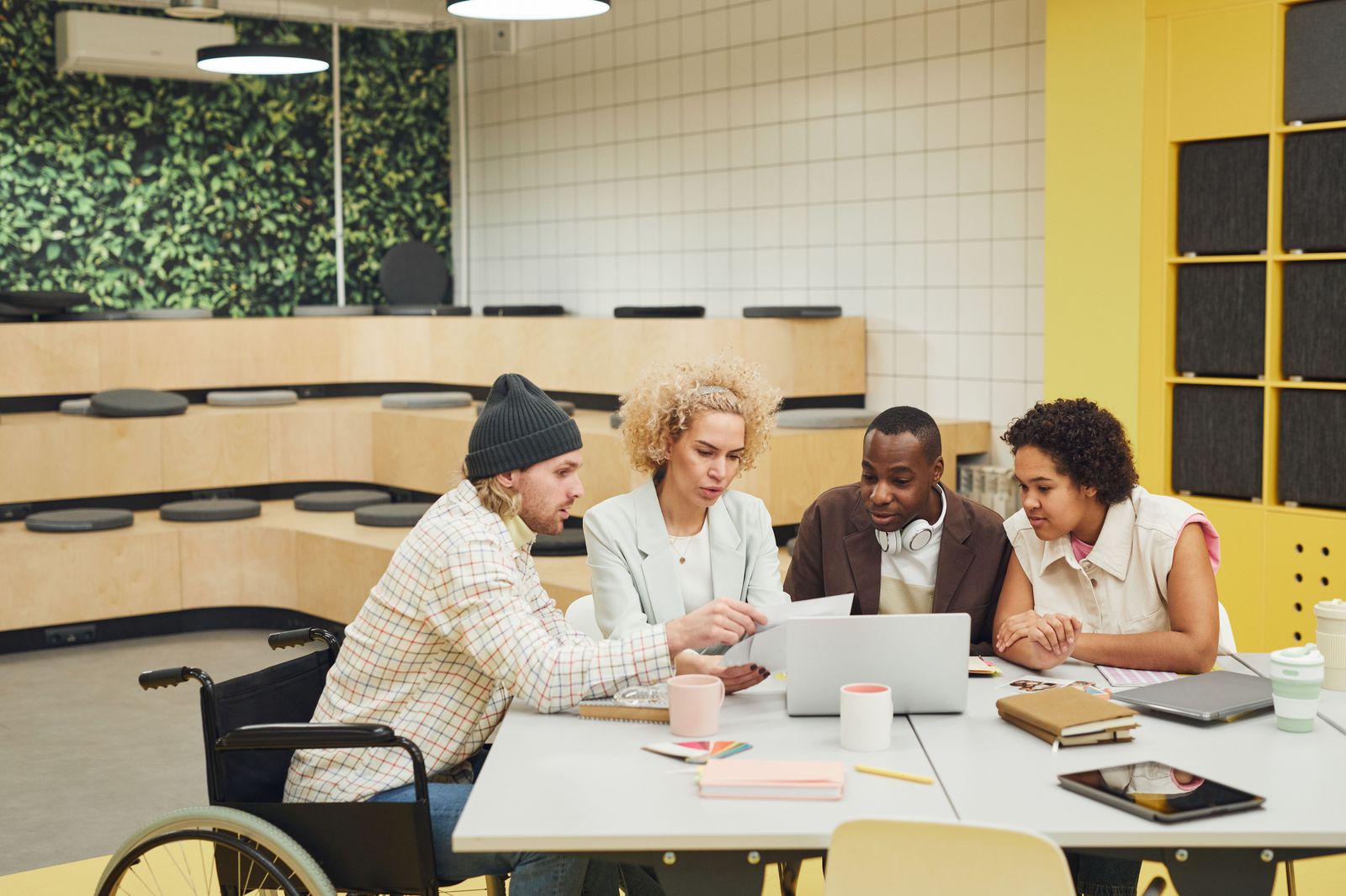 Diverse small business team collaborating around a table reviewing work on a laptop