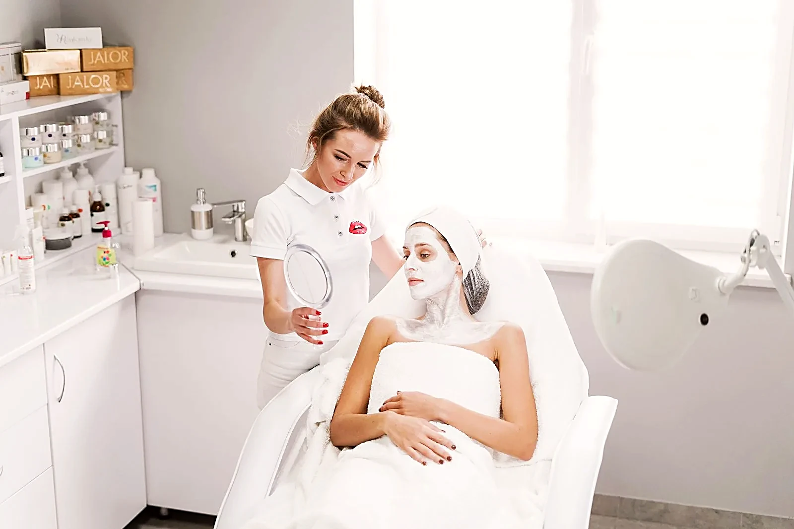 Esthetician showing facial treatment results to a client in a modern beauty clinic
