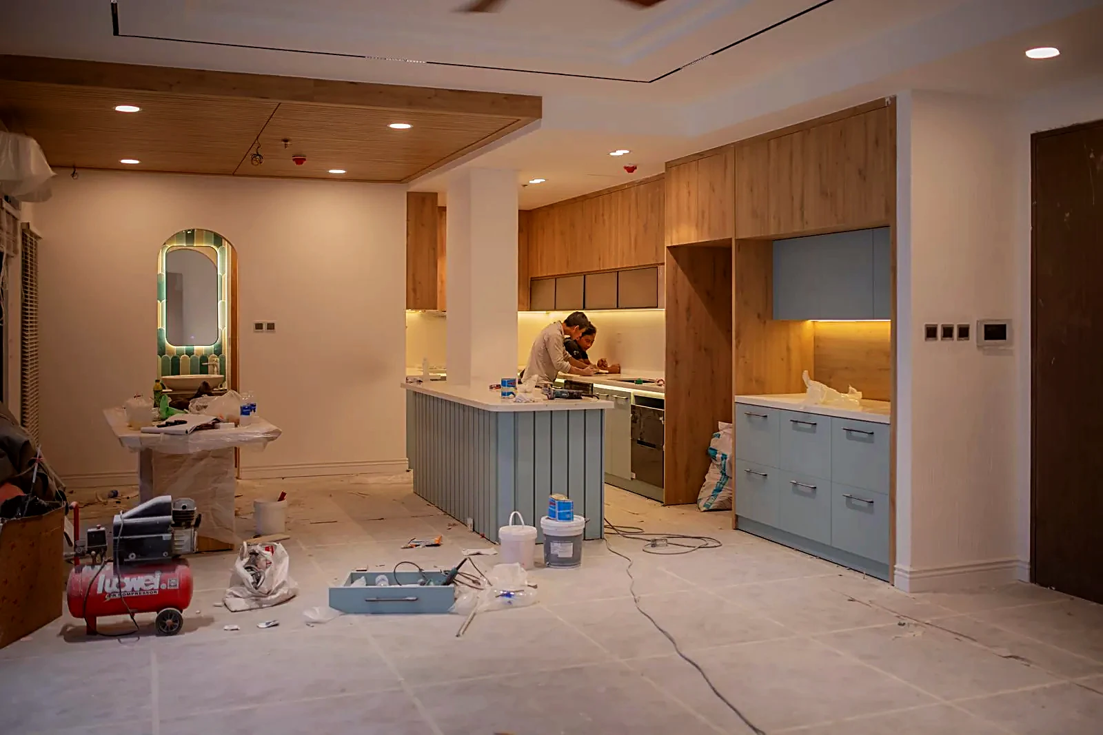 Two workers installing a kitchen in a home under renovation