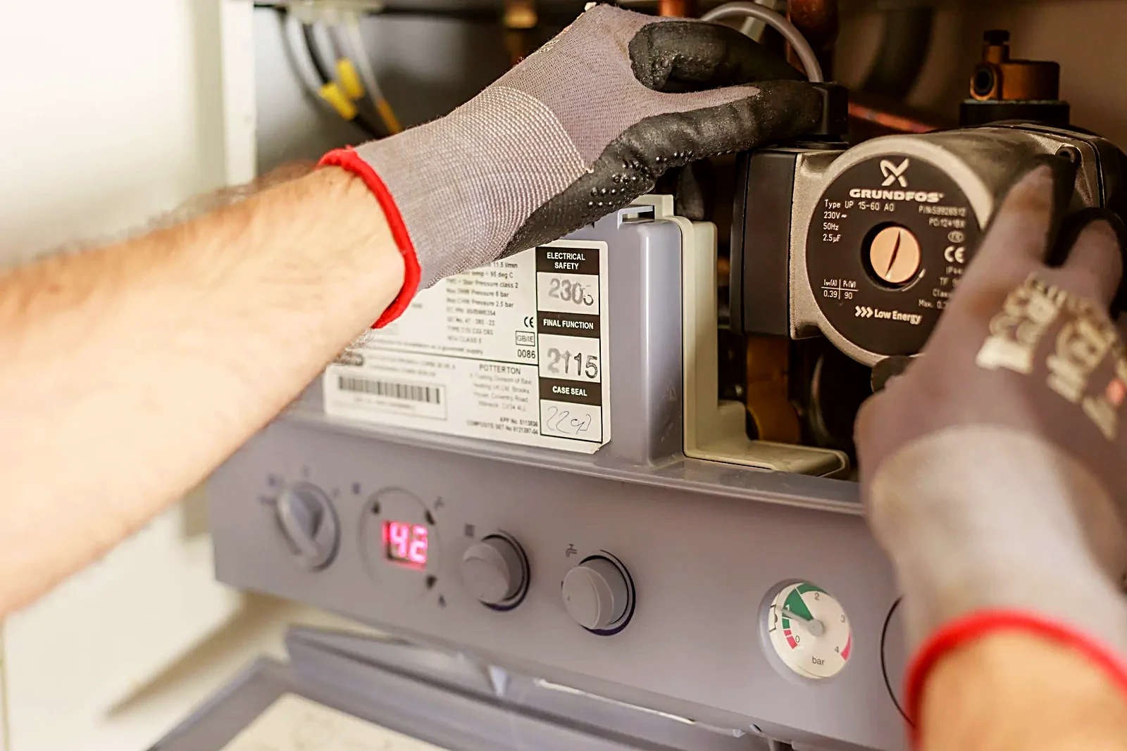 Technician's gloved hands servicing a residential heating boiler