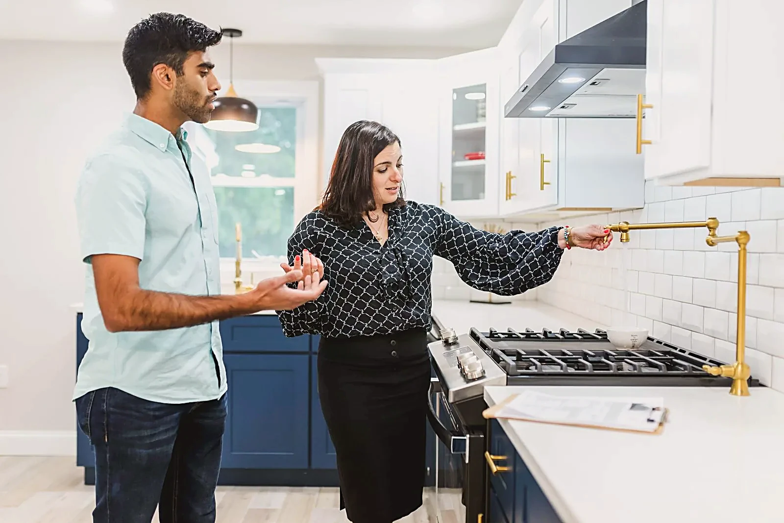 Real estate agent showing a home buyer around a modern kitchen