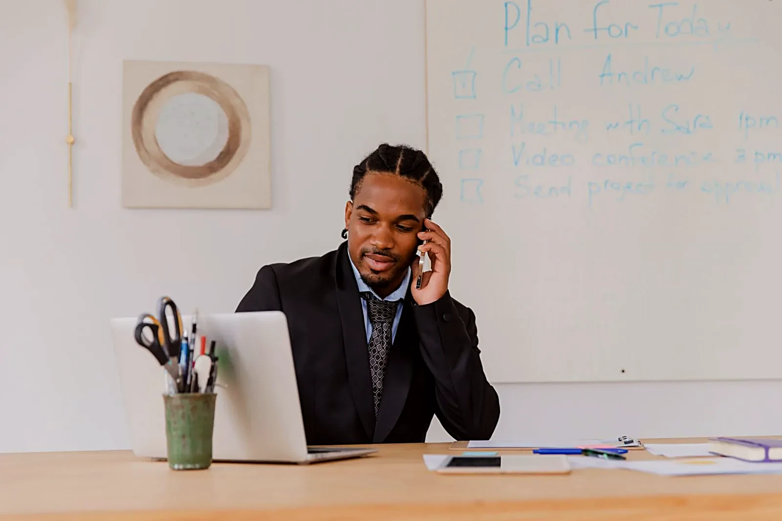 Man on a phone call at his desk with a planning whiteboard behind him