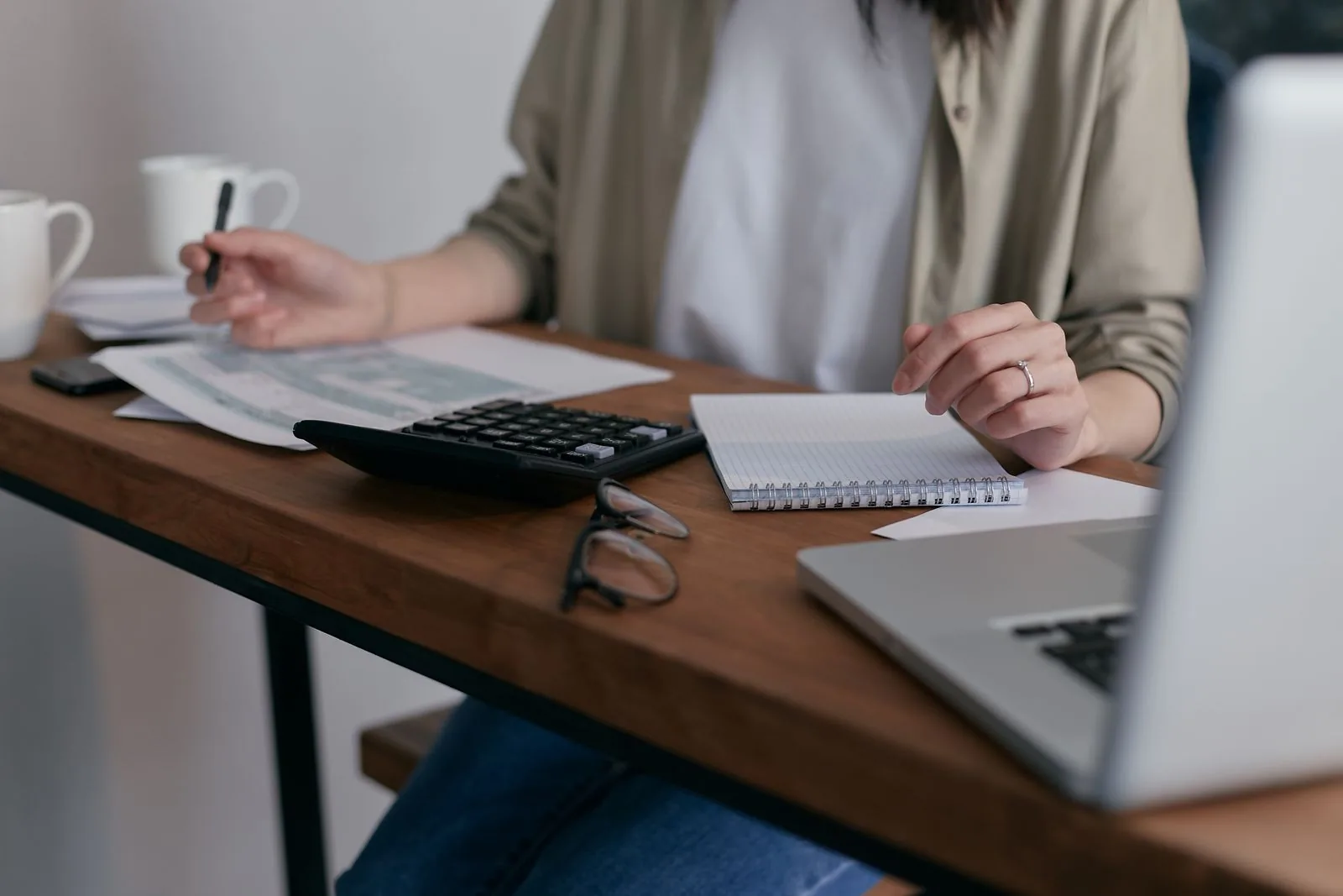 Woman at a desk with a calculator, invoices, and a laptop