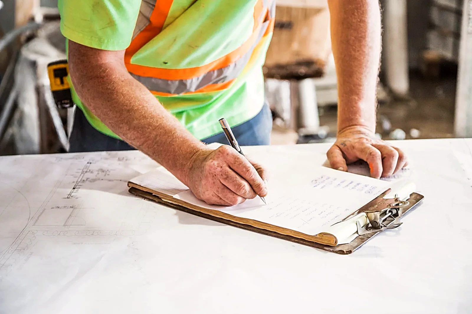 Worker in a hi-vis vest writing on a clipboard