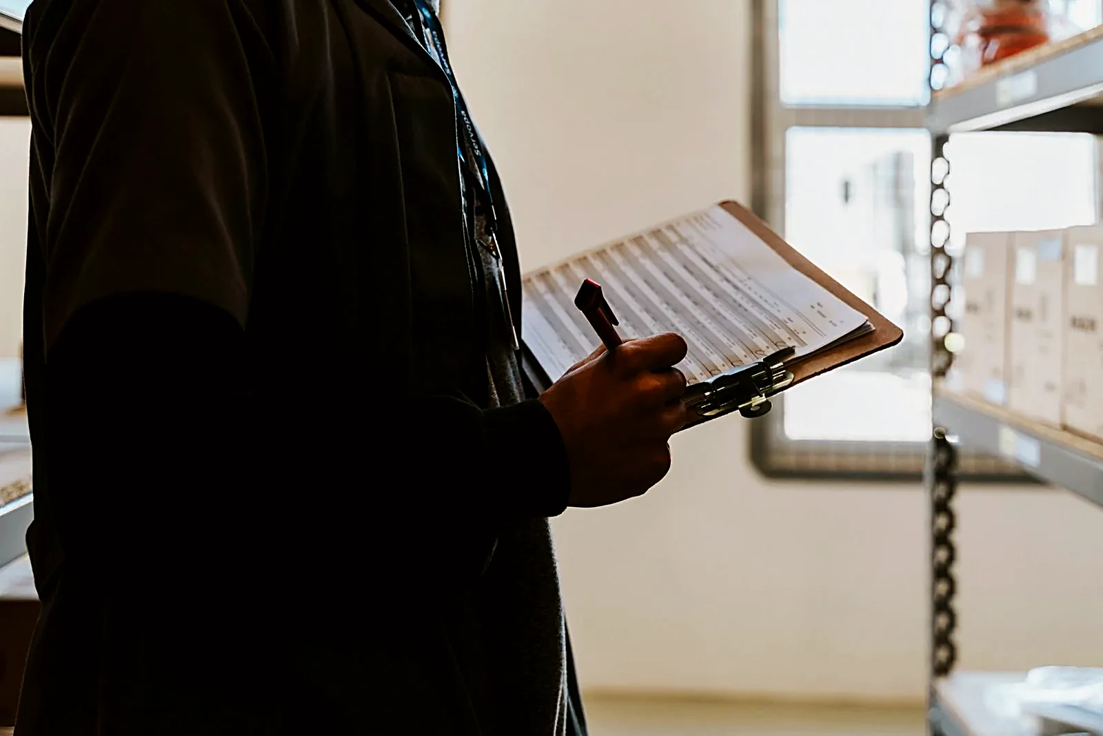 Technician holding a clipboard next to parts shelving