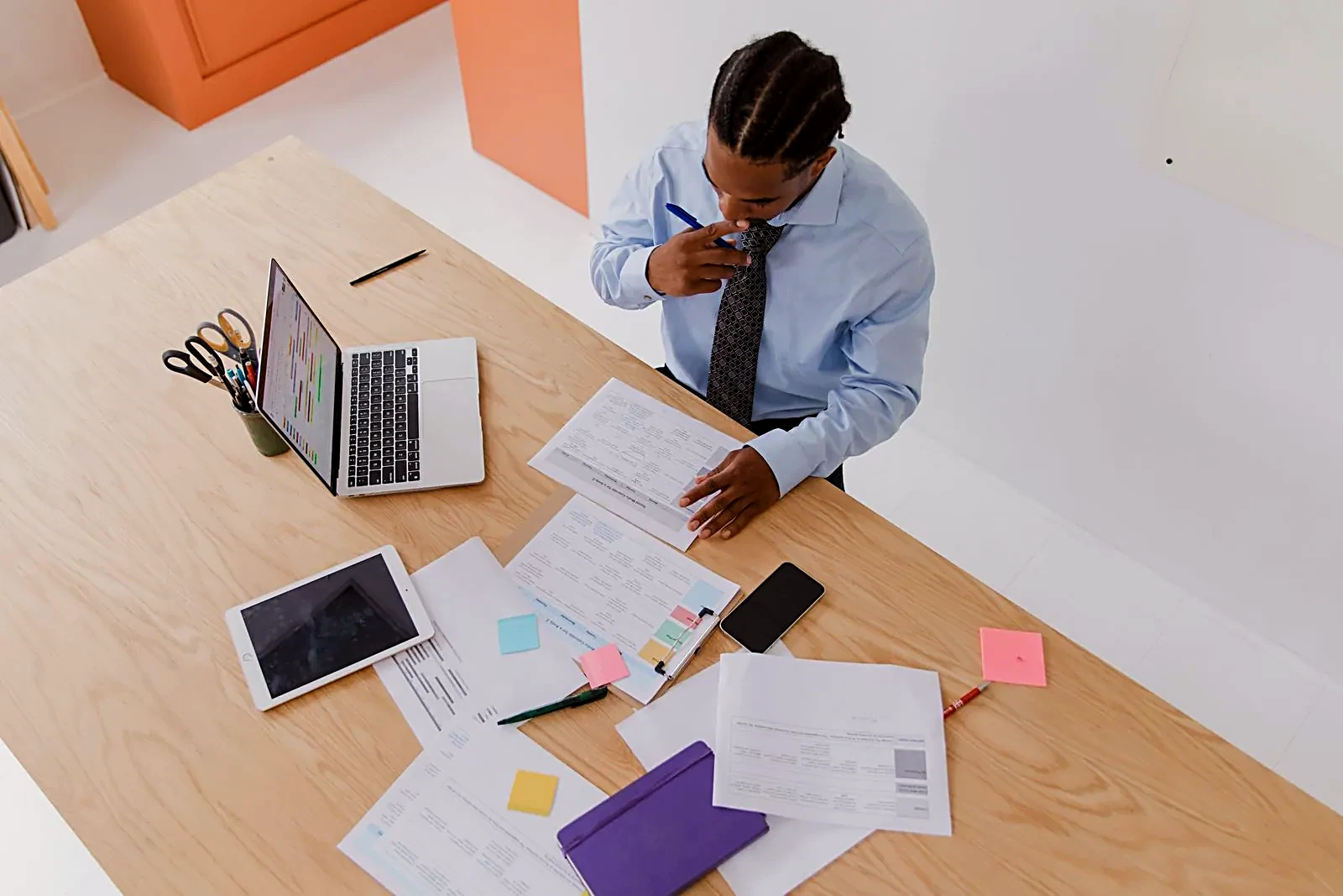 Man reviewing paperwork at a desk with a laptop and tablet