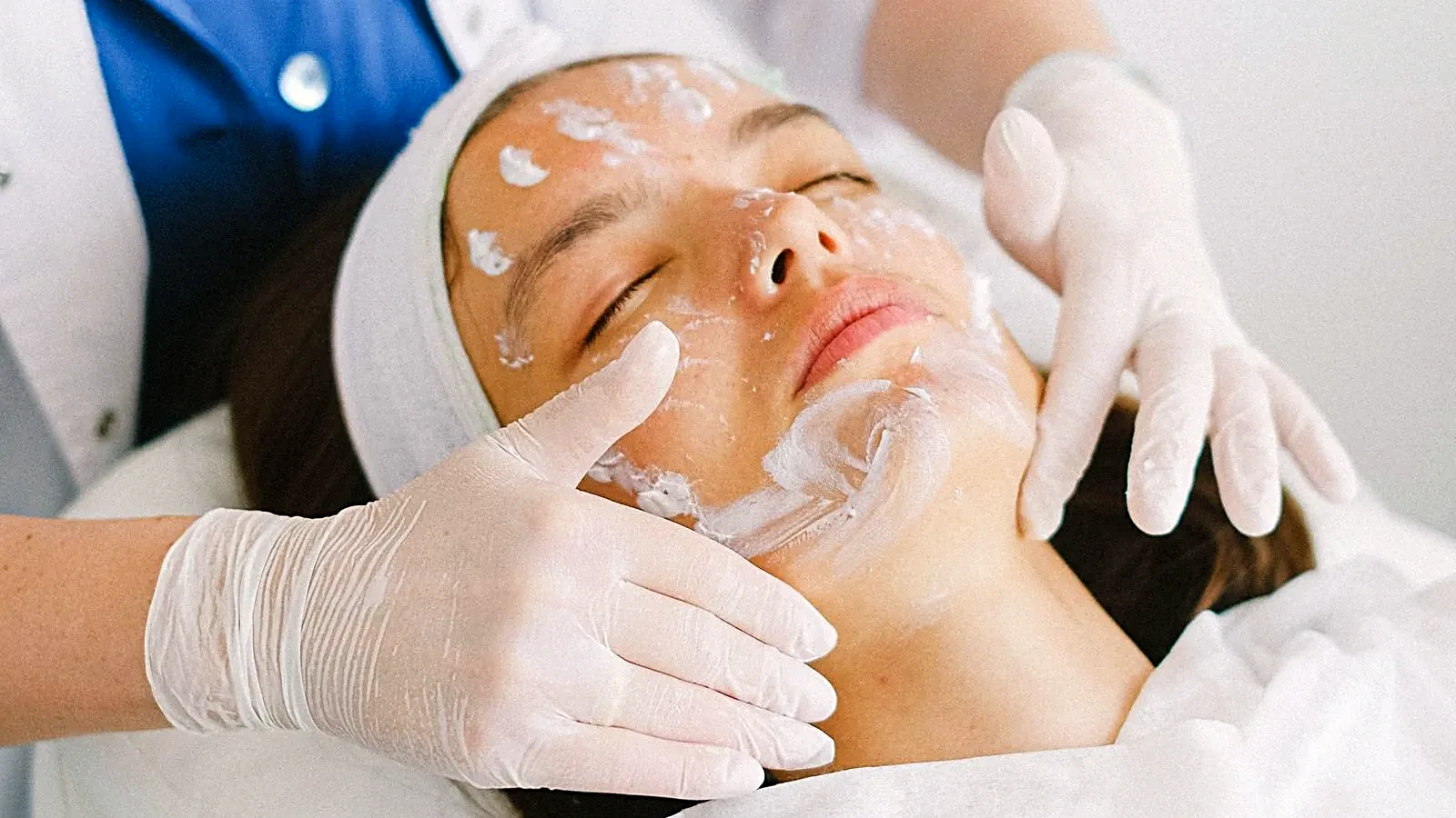 Cosmetologist applying a facial mask to a client in a spa salon