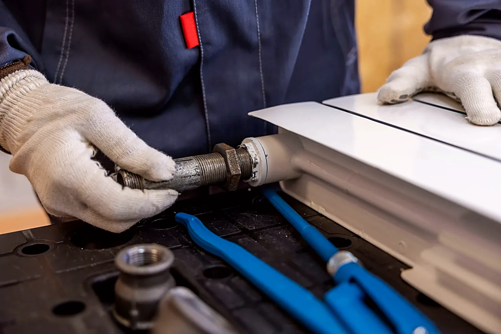Plumber installing a radiator pipe with specialized tools