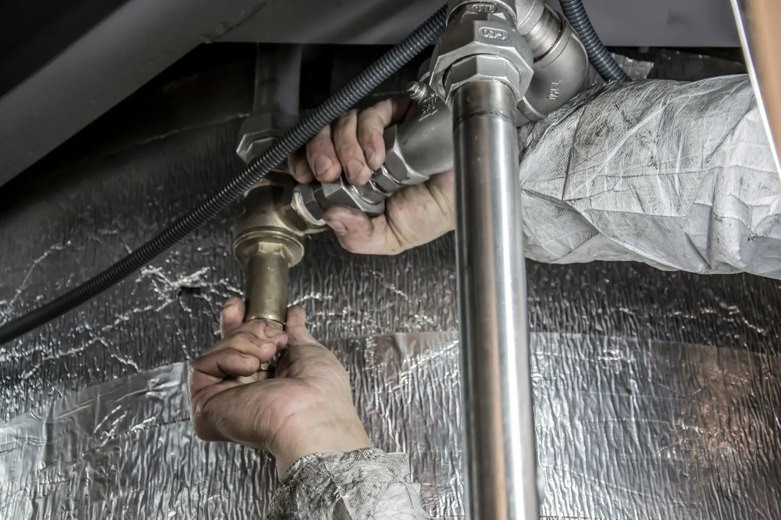 Plumber's hands installing steel pipes