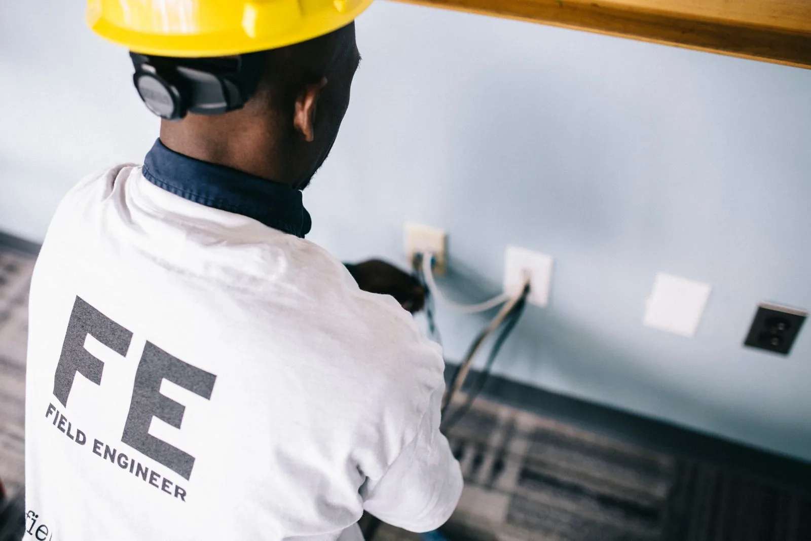 Electrician in a hard hat wiring wall outlets