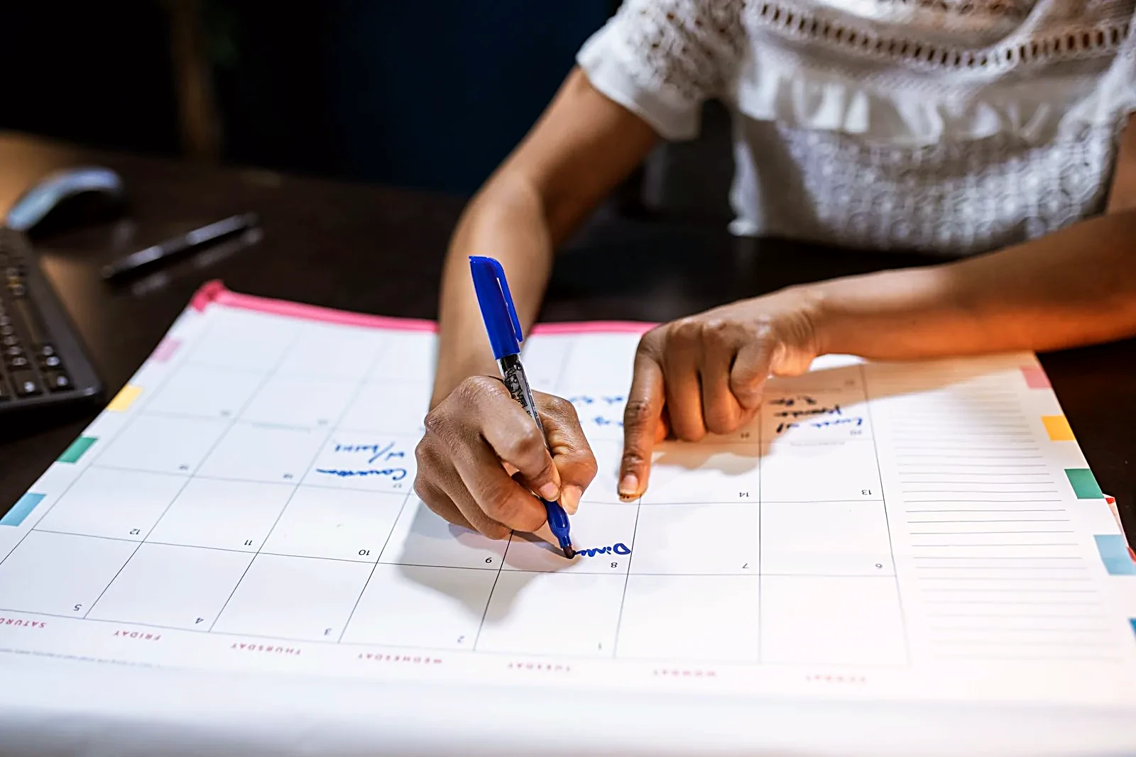 Woman writing on a large desk calendar with a pen